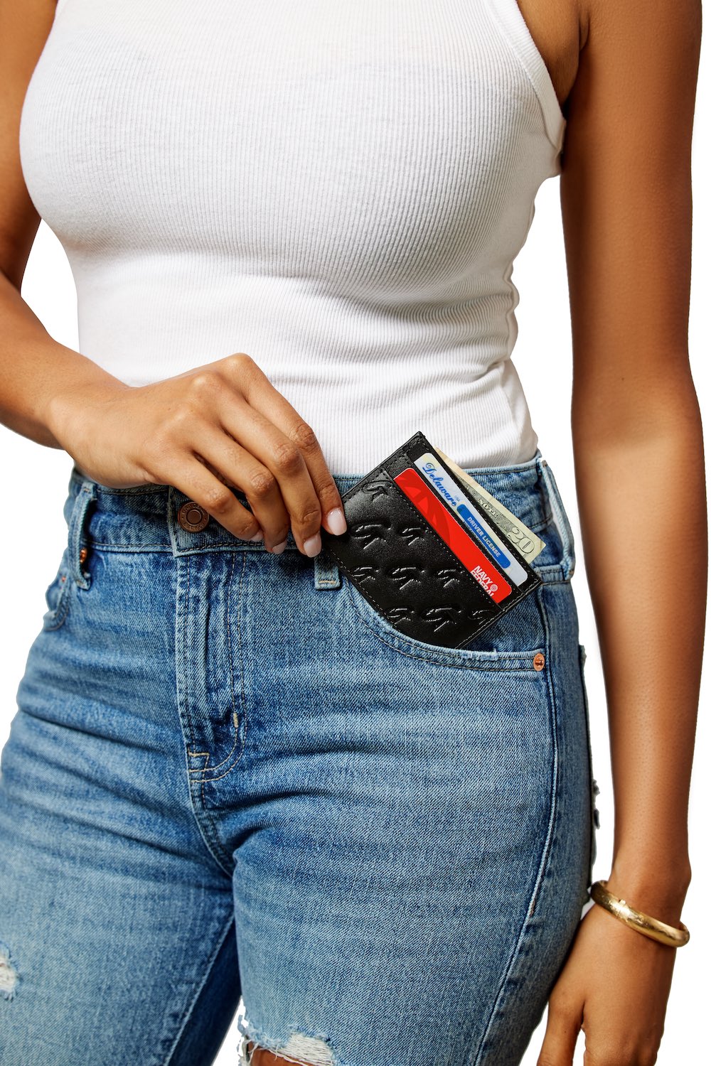 Black matte monogram card holder with embossed logo, partially visible in a person's front pocket.