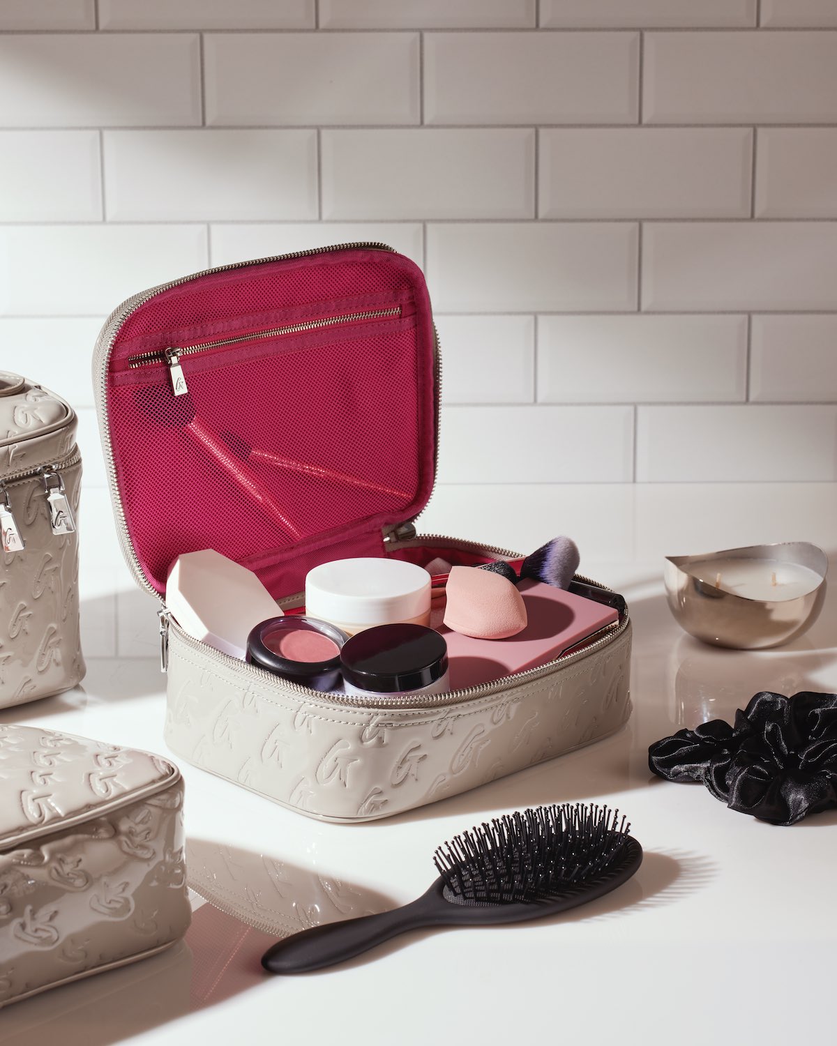 Medium monogram toiletry bag in mirror gray with pink interior, open to reveal skincare products and accessories inside.