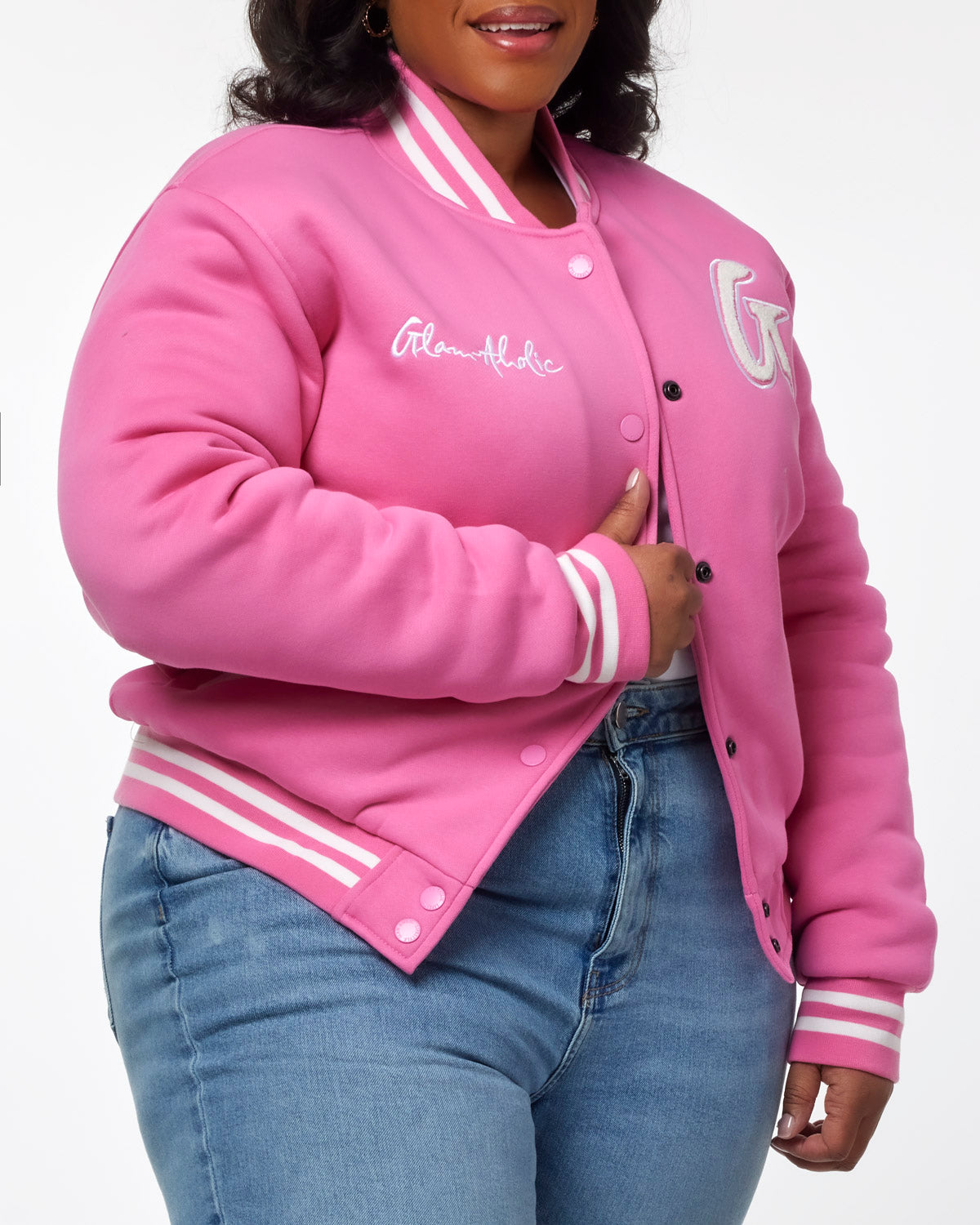 Hot pink varsity jacket with white stripes and logo, styled with casual denim for a trendy look.