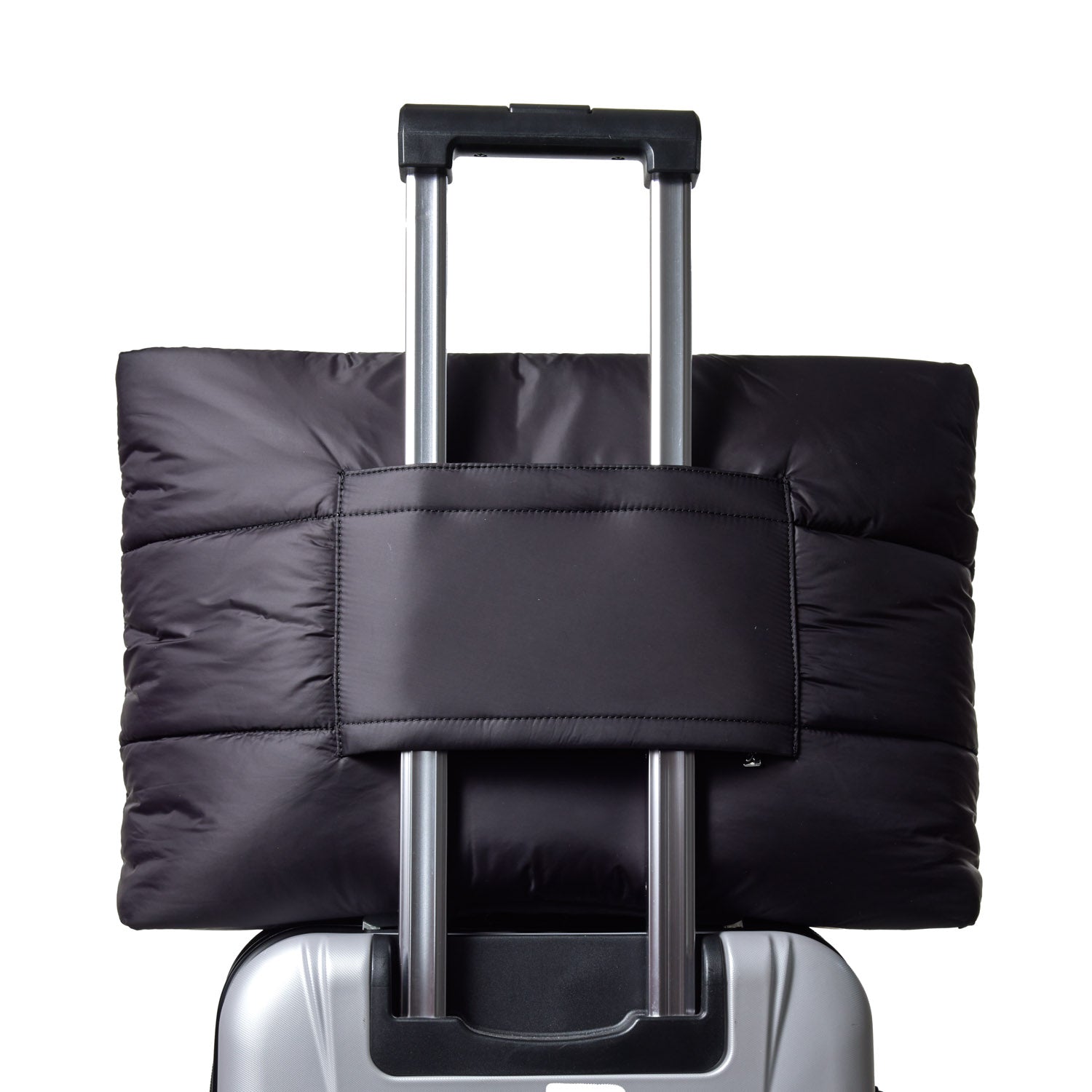 Black athletic nylon tote secured on the handle of a silver suitcase, showcasing its sleek design and functionality.