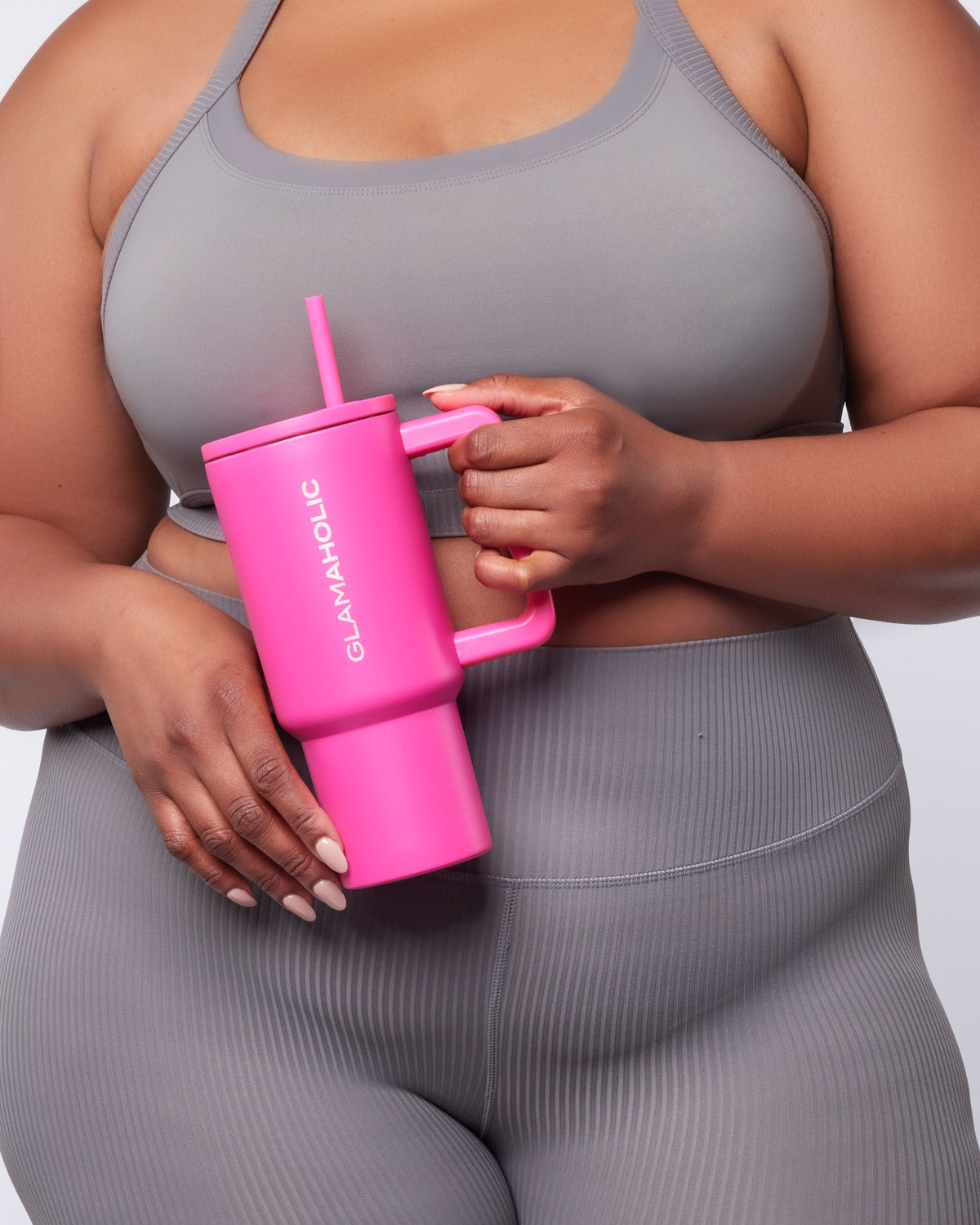 Hot pink athletic tumbler held by a person in a gray sports bra and leggings, showcasing a stylish fitness accessory.