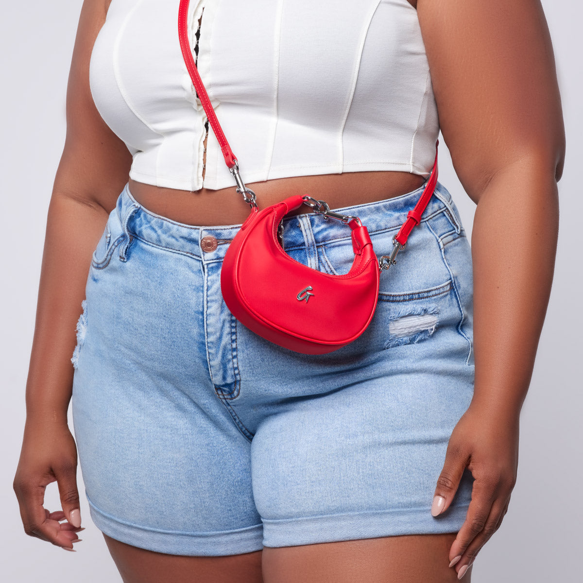 Red nano nylon hobo bag worn crossbody with a white crop top and denim shorts, showcasing a stylish casual look.