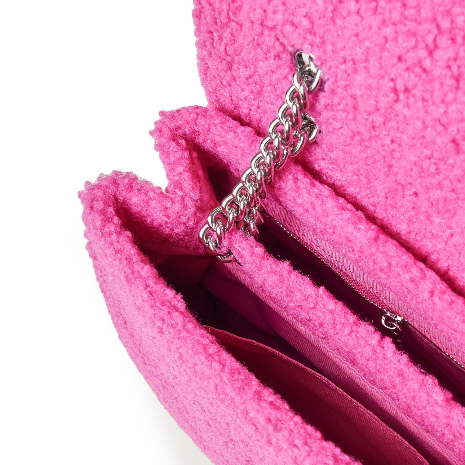 Close-up of a pink teddy flap bag with a silver chain strap and interior zip pocket, showcasing soft, textured fabric.