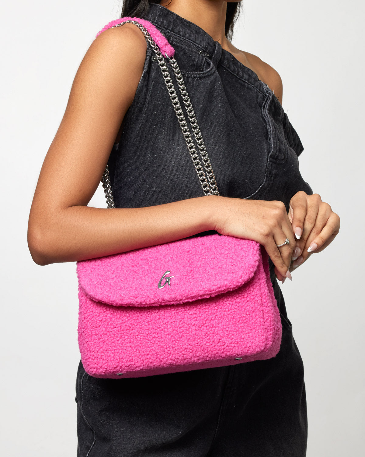 Medium hot pink teddy flap bag with a silver chain strap, worn over a black sleeveless top.