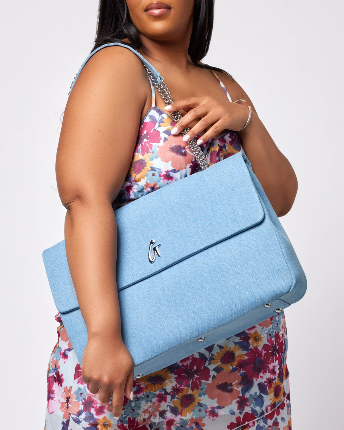 Large light blue denim flap bag with silver hardware and chain strap, featuring a silver logo on the front.