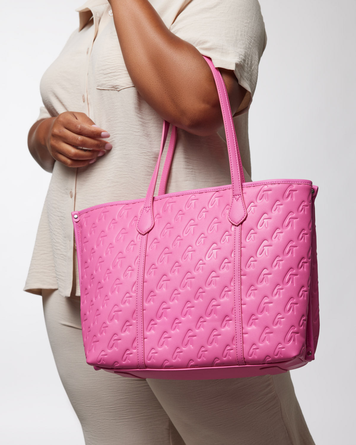 Pink Monogram Sleek Tote bag with embossed G pattern, carried by a woman in a beige outfit.