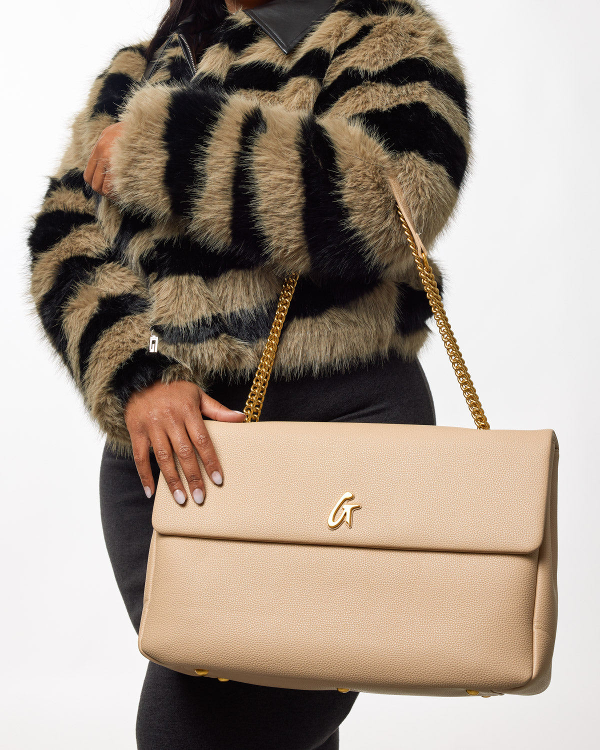 Beige XL Pebble Flap Bag with gold chain strap and "G" logo, held by a woman in a fur striped jacket.