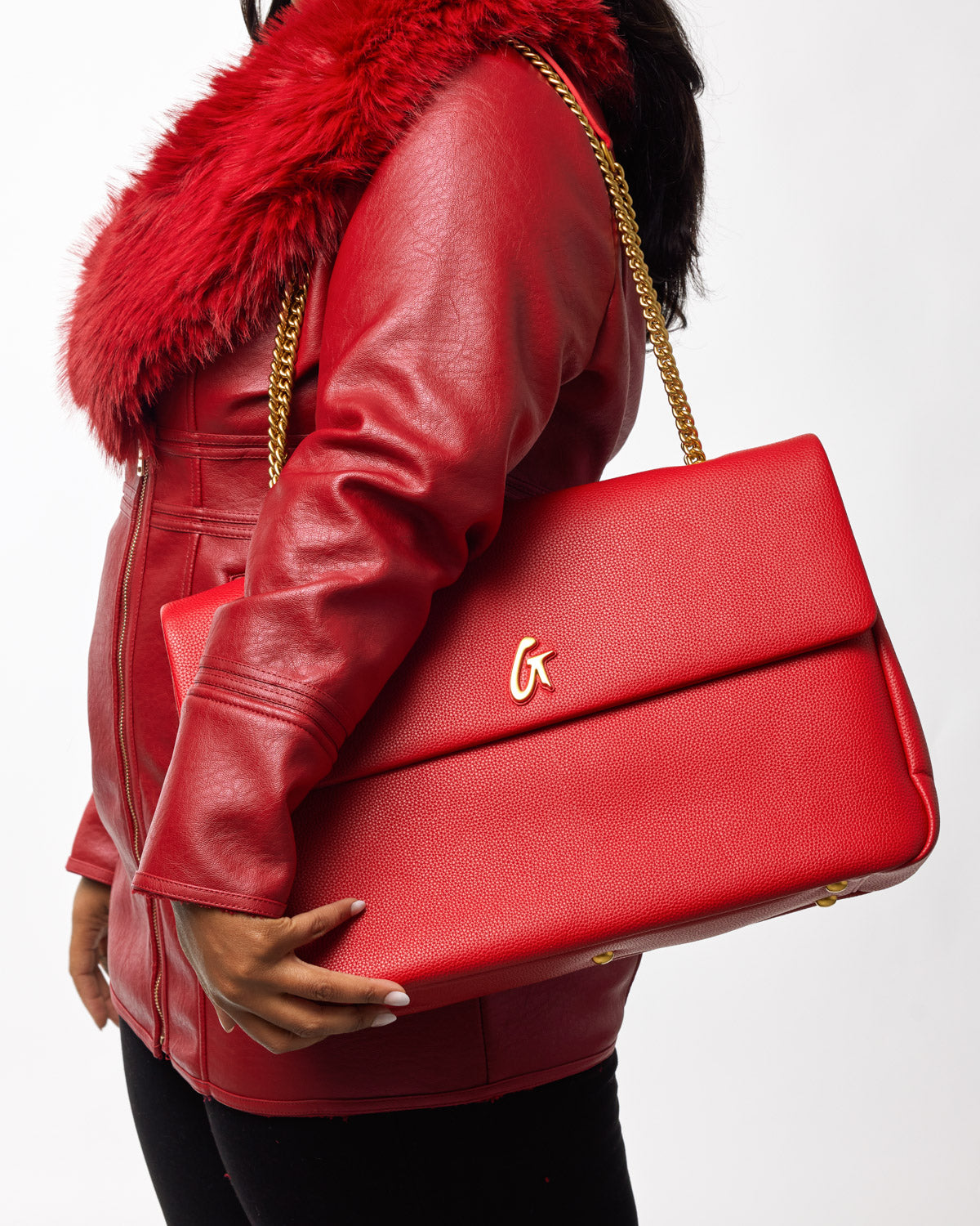 Red XL Pebble Flap Bag with gold chain strap, held by a person in a red leather jacket with fur collar.