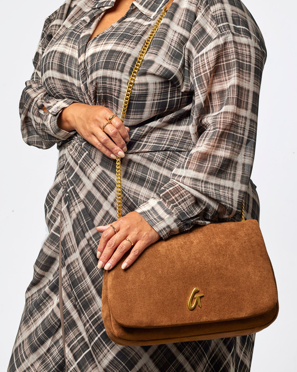 Brown medium suede flap bag with gold chain strap, styled with a plaid dress for a chic, affordable luxury look.