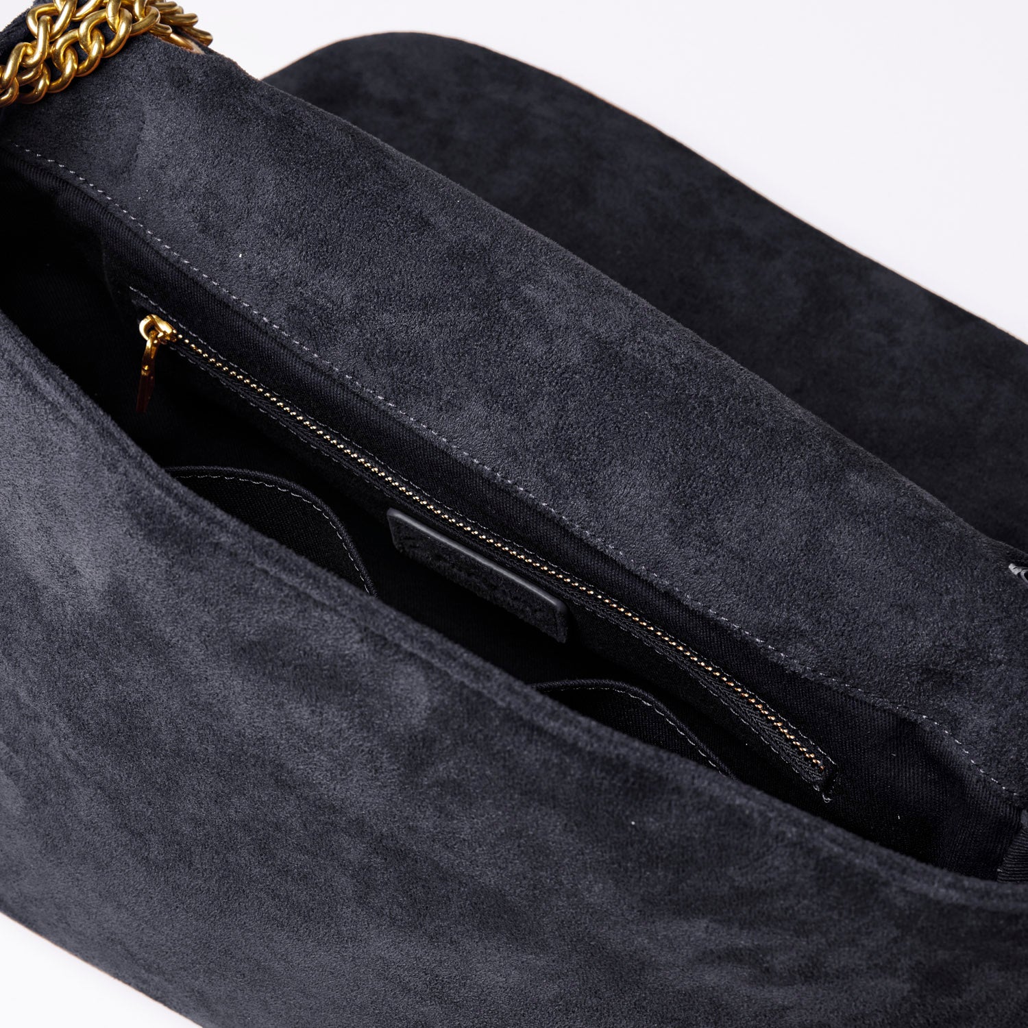 Medium black suede flap bag featuring a gold chain strap and spacious interior with zippered pocket.