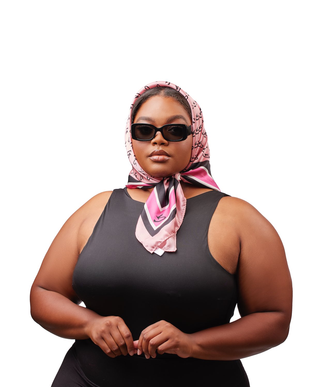 Large pink silk monogram scarf with black and white accents, styled around a woman's head and neck.