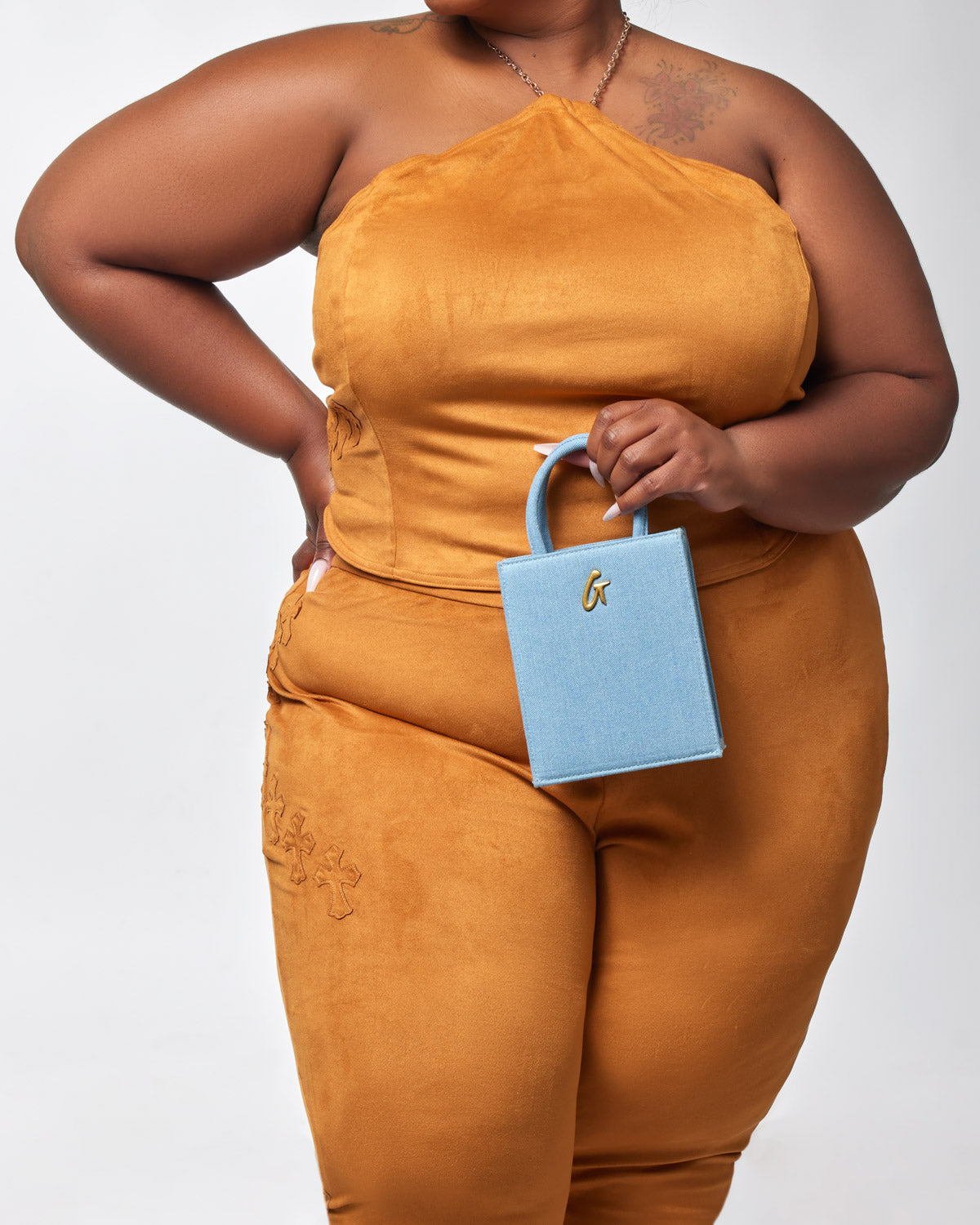 Mini denim gold tote bag with a small handle, featuring a gold "G" logo, held by a woman in a mustard-colored outfit.