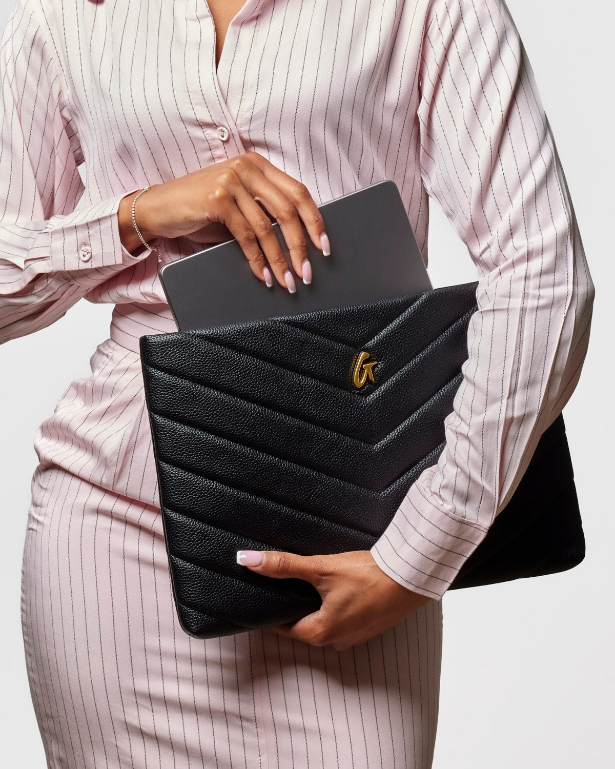 Chic black pebble laptop sleeve with chevron design, elegantly held by a woman in a striped blouse.
