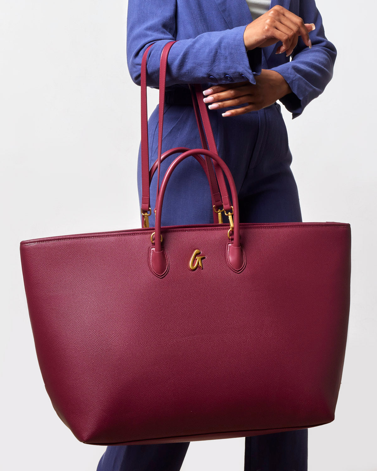 Jumbo burgundy pebble tote bag with dual handles and gold logo, perfect for stylish everyday use.