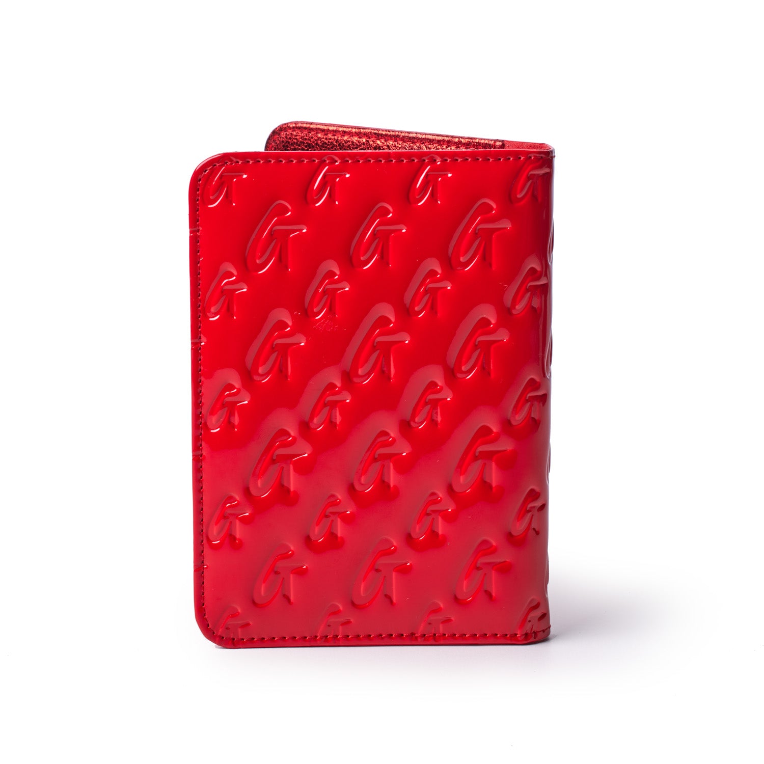 Red mirror finish passport holder with embossed monogram G pattern, designed for stylish travel accessories.