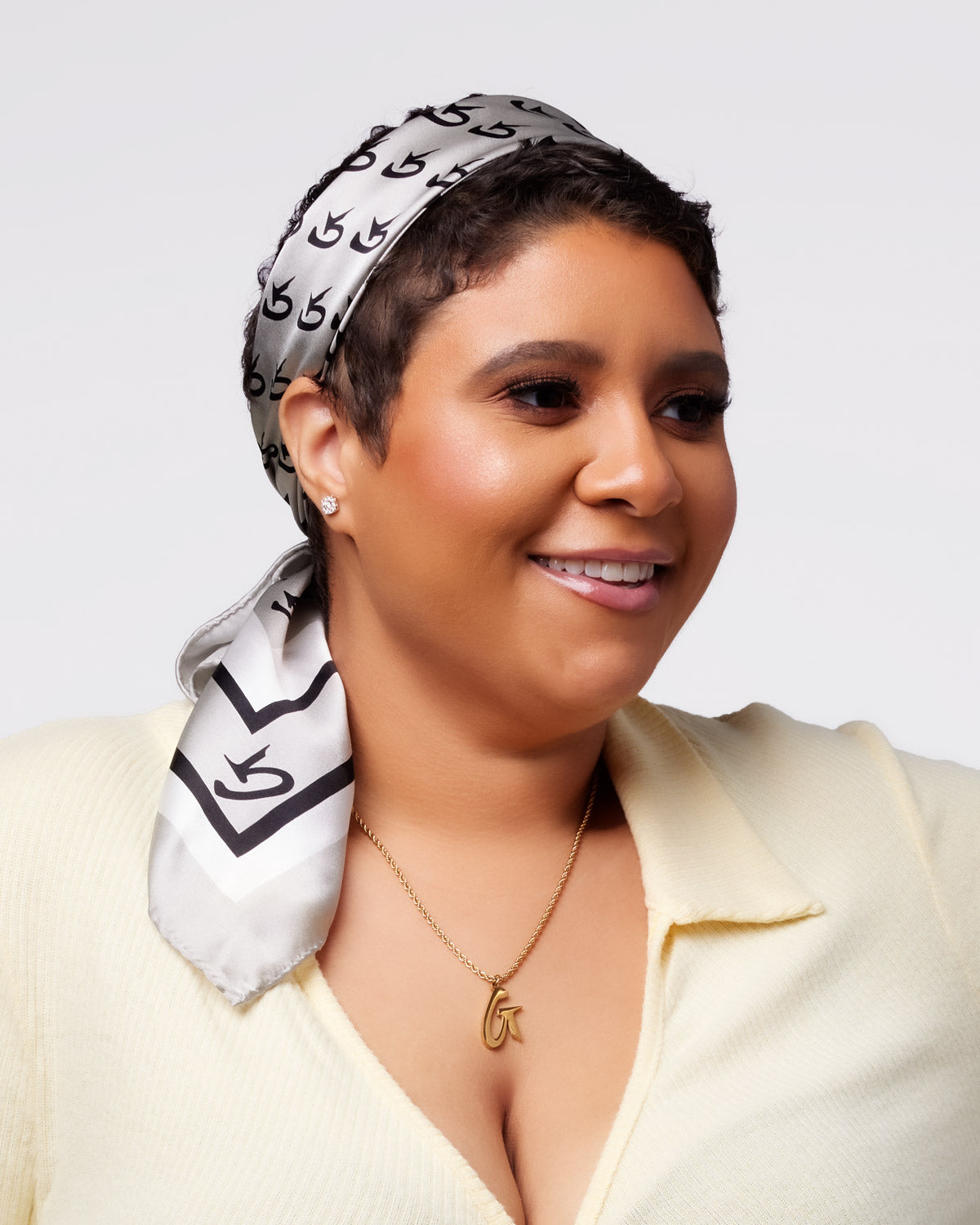 Medium monogram silk scarf in silver styled elegantly around a woman's head, showcasing a chic and sophisticated look.