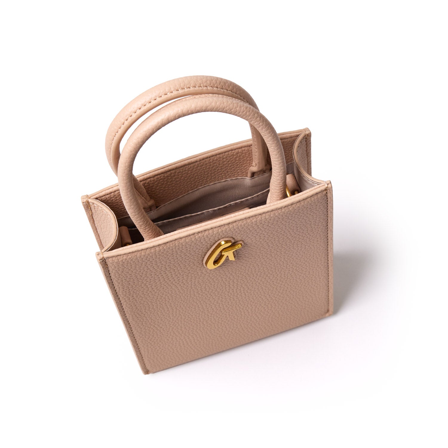 Mini pebble tote bag in nude color with gold logo detail, featuring textured leather and dual top handles.