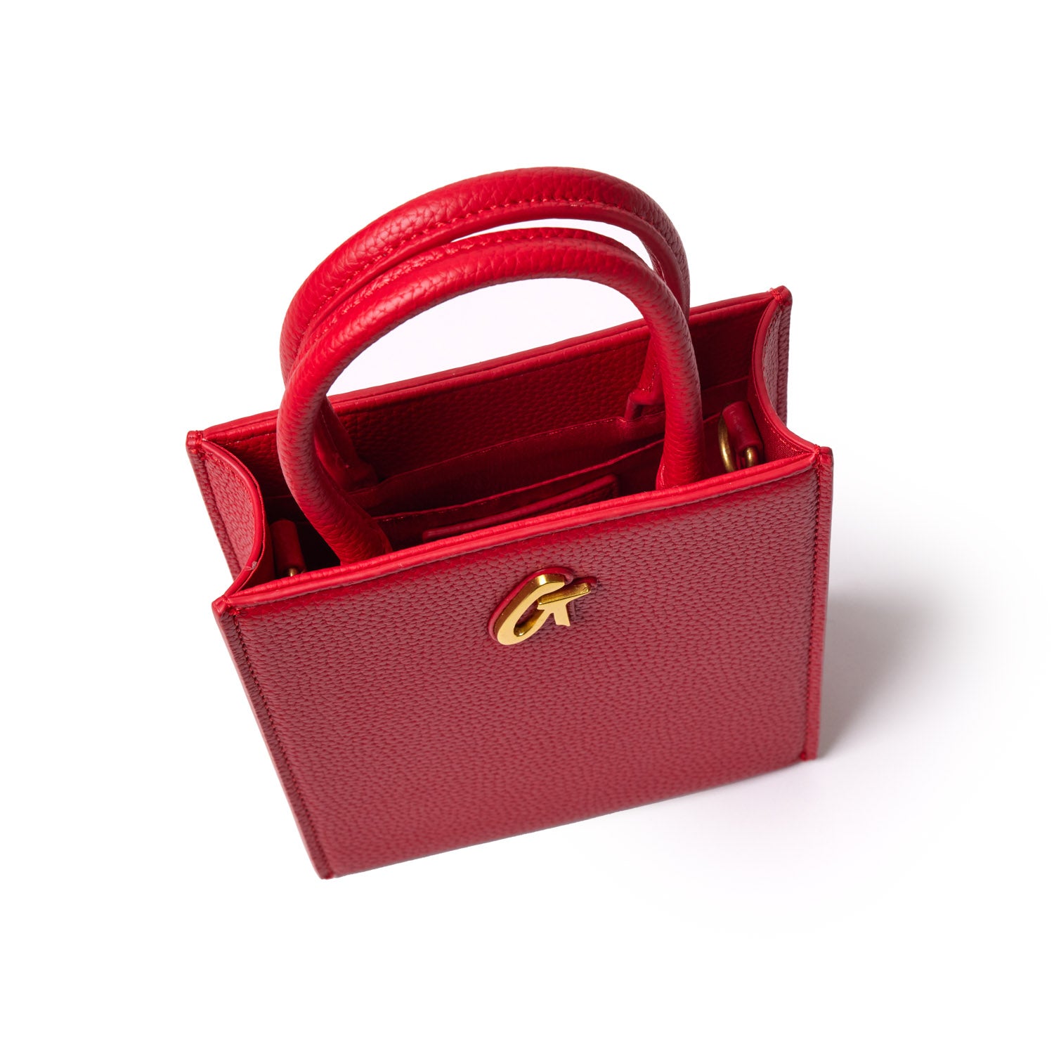 Red mini pebble tote bag with dual top handles, gold logo detail, and interior compartments on a white background.