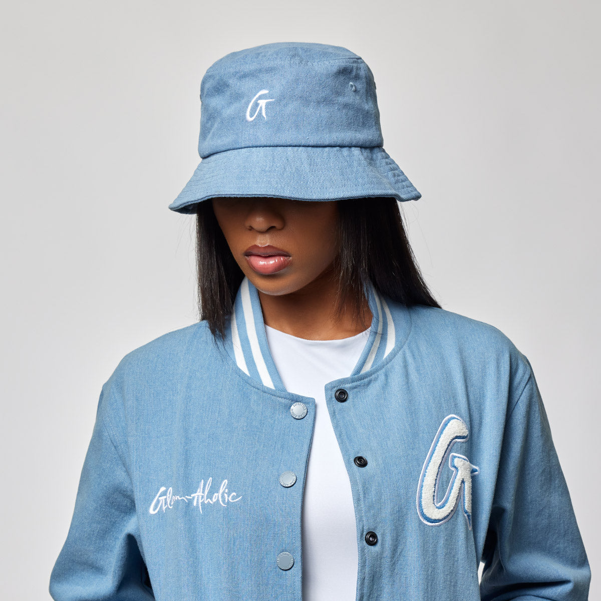 Blue denim bucket hat with a white embroidered logo, worn by a woman in a matching denim jacket.
