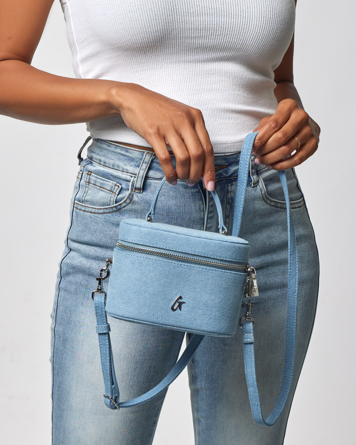 Mini denim silver vanity bag with a zip closure, adjustable strap, and a small front logo, worn crossbody style.