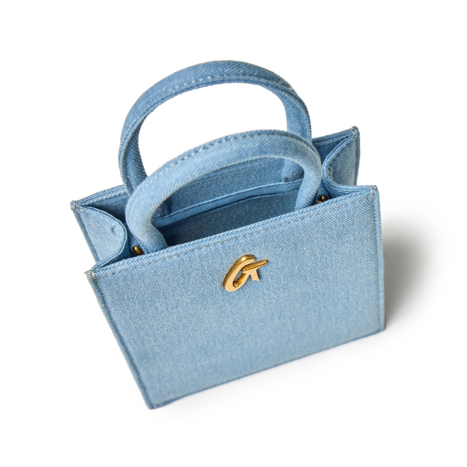 Mini denim gold tote bag with two handles, gold logo detail, and compact design on white background.