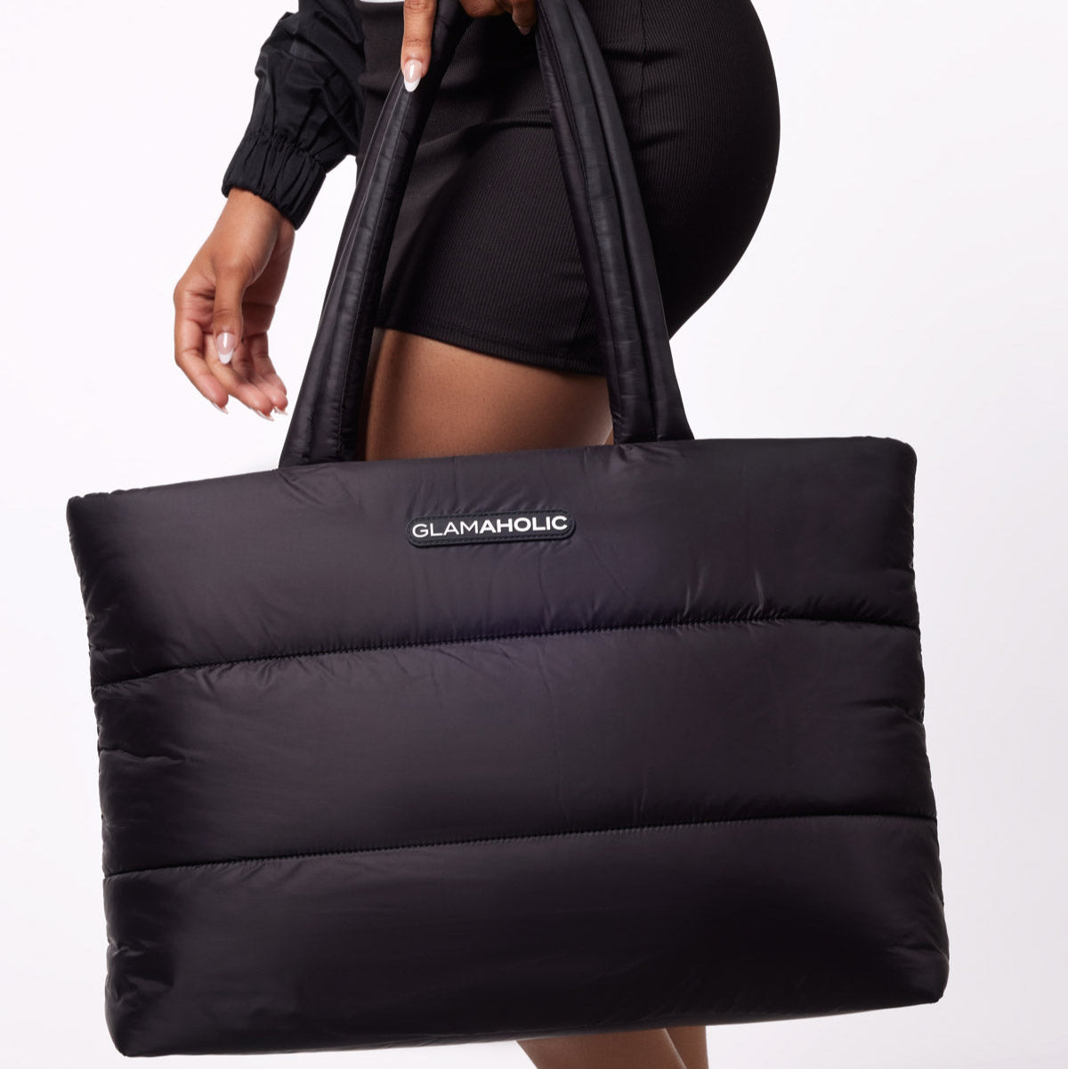 Black athletic nylon tote bag held by a model, featuring a padded design and the Glam-Aholic logo.