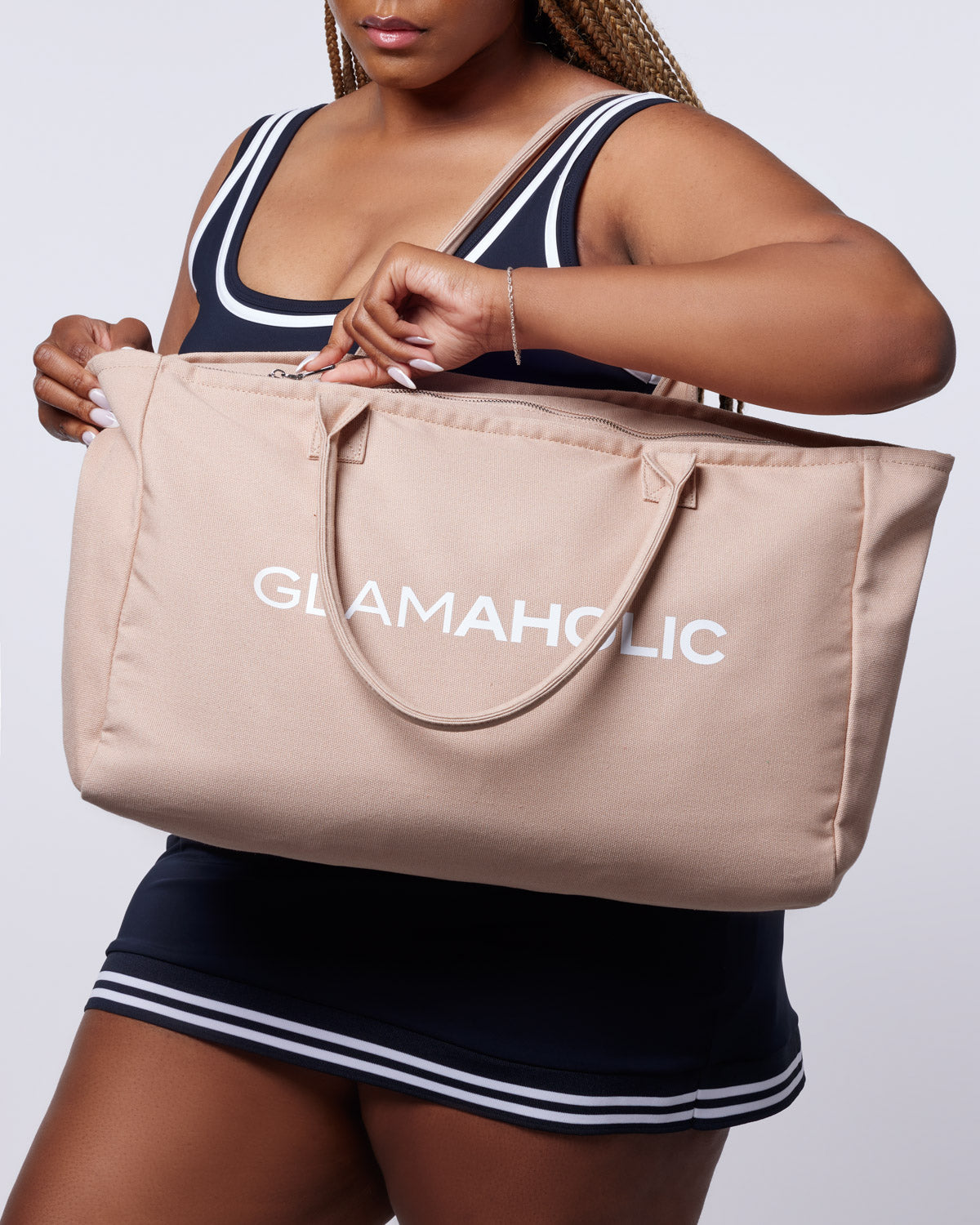 Nude athletic canvas tote bag with "GLAMAHOLIC" logo, held by a person wearing a sporty outfit.