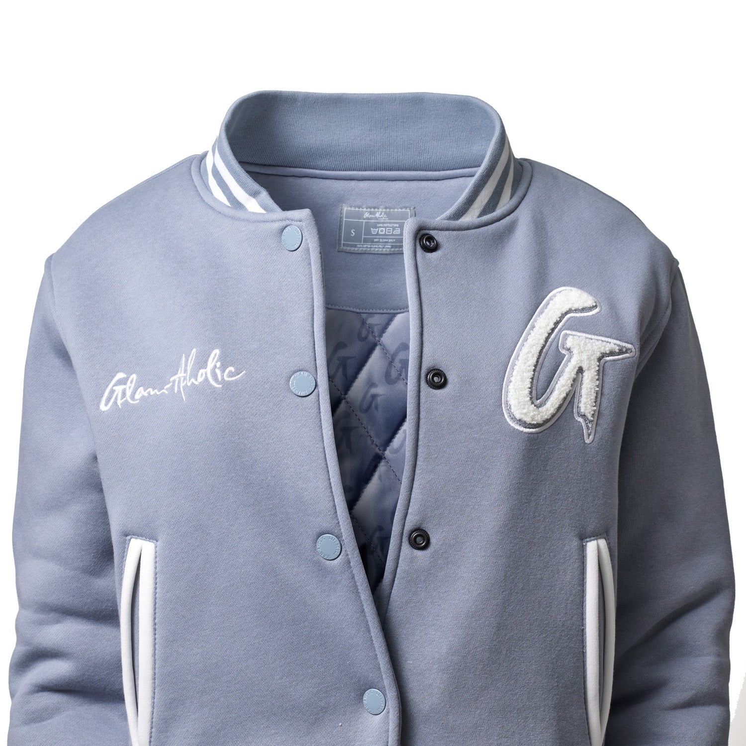 Gray varsity jacket with embroidered patches, white accents, and snap buttons, featuring a quilted inner lining.