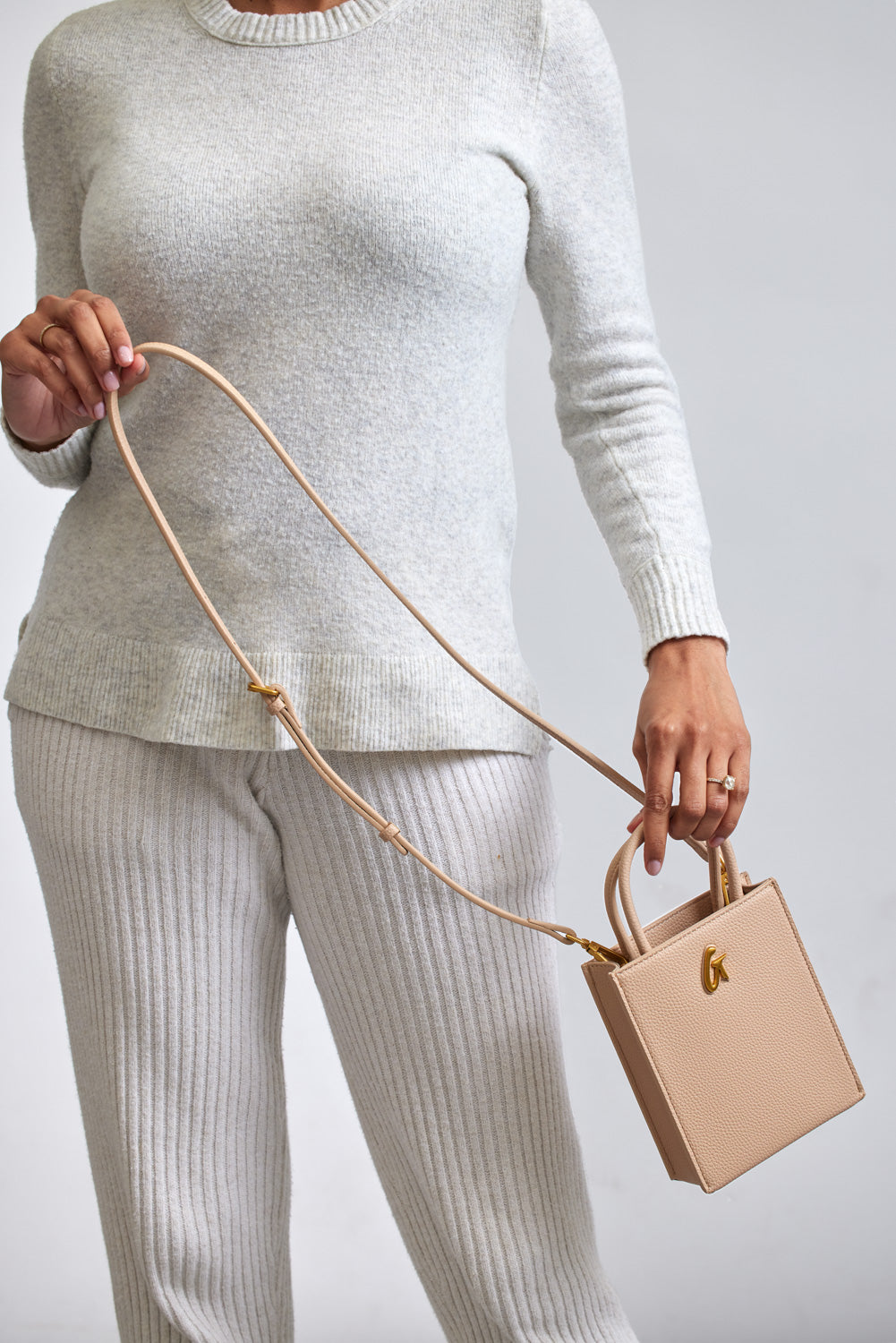 Mini Pebble Tote in nude color with a structured, textured design, held by a woman dressed in cream knitwear.