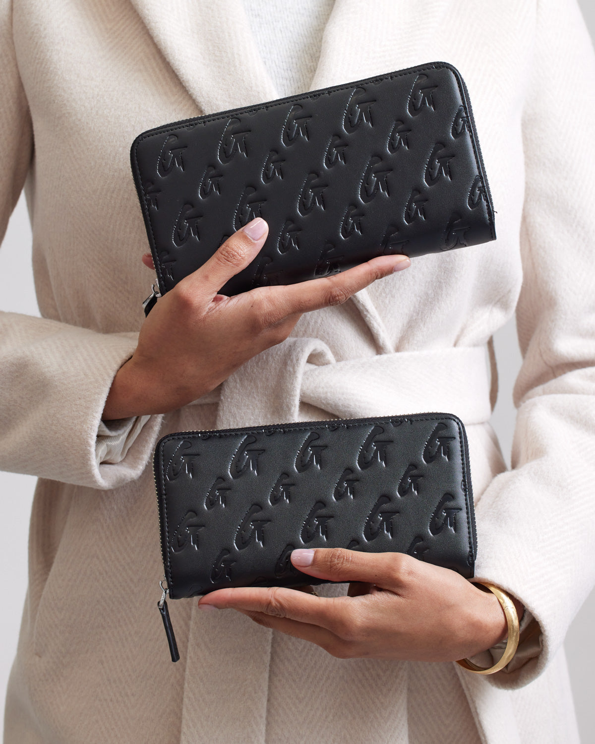 Two women hold black matte wallets with embossed G monogram pattern, showcasing the stylish Jumbo Monogram Wallet design.