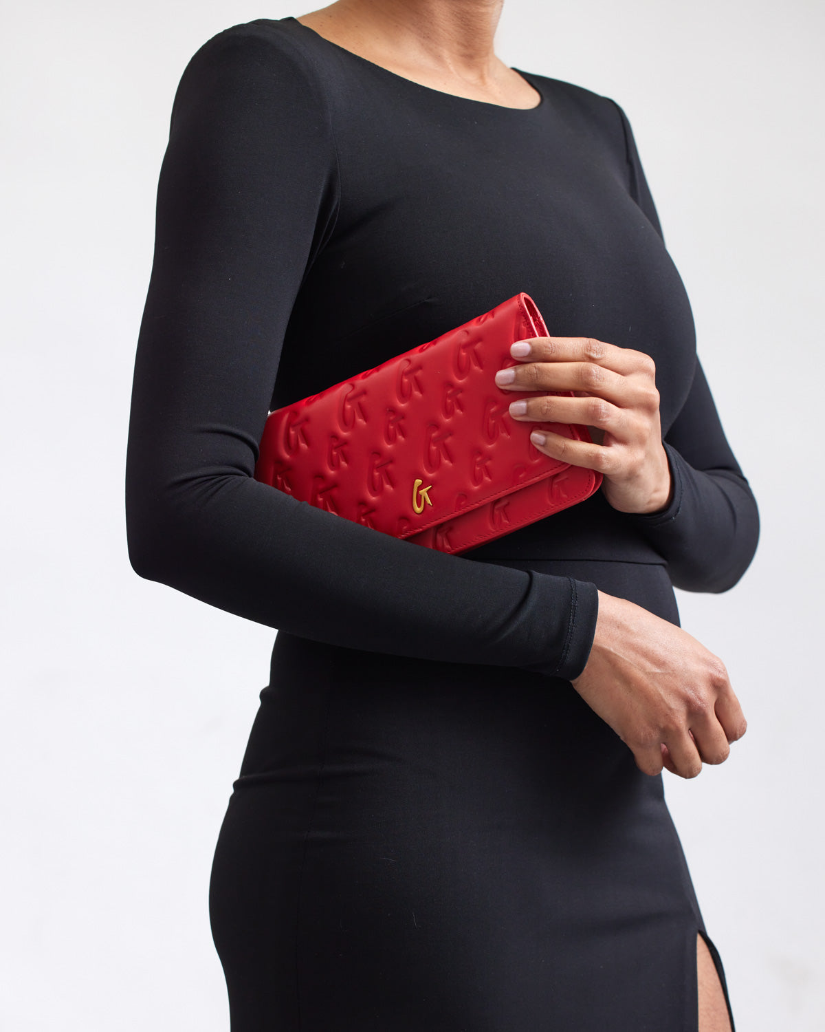 Red Monogram Gold WOC clutch with embossed G pattern and gold logo, held by a woman in a black dress.