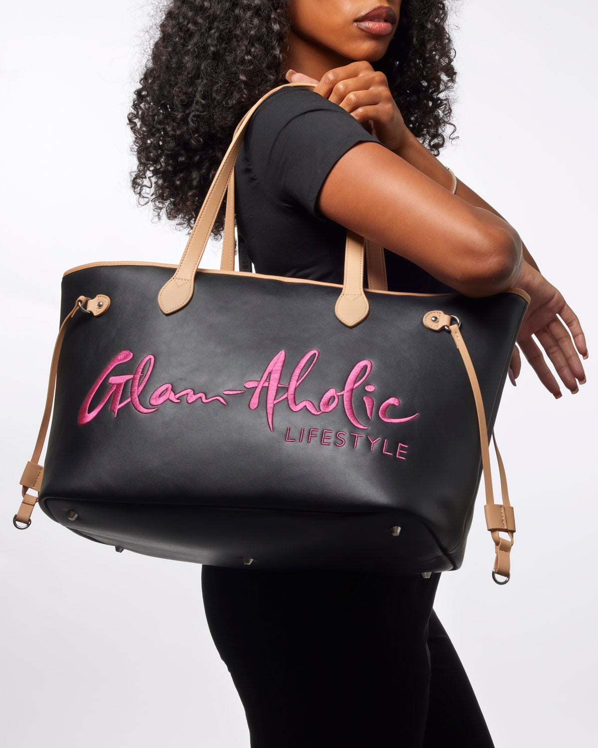 Black and pink Glam-Aholic tote bag held by a model, featuring stylish branding and sleek design for everyday use.