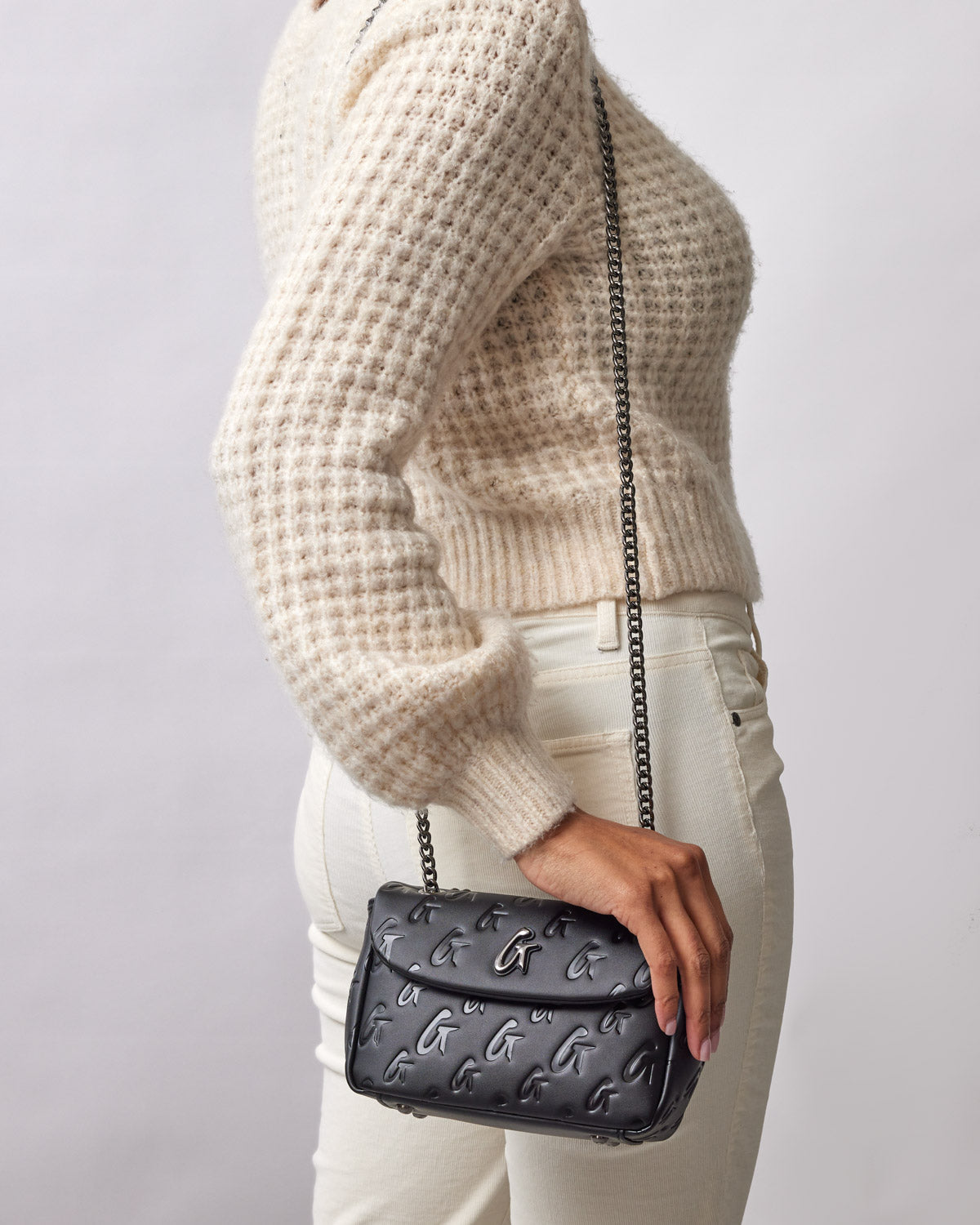 Black mini monogram flap bag with embossed G logo pattern, worn crossbody with a chain strap.