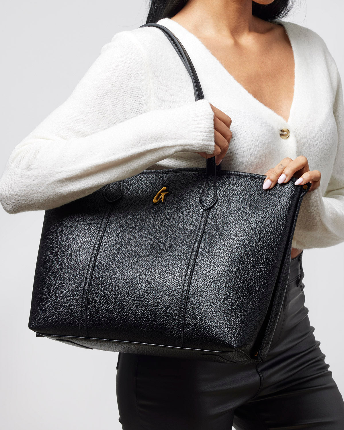 Stylish black Pebble Sleek Tote held by a woman, featuring a textured finish and elegant design for everyday use.
