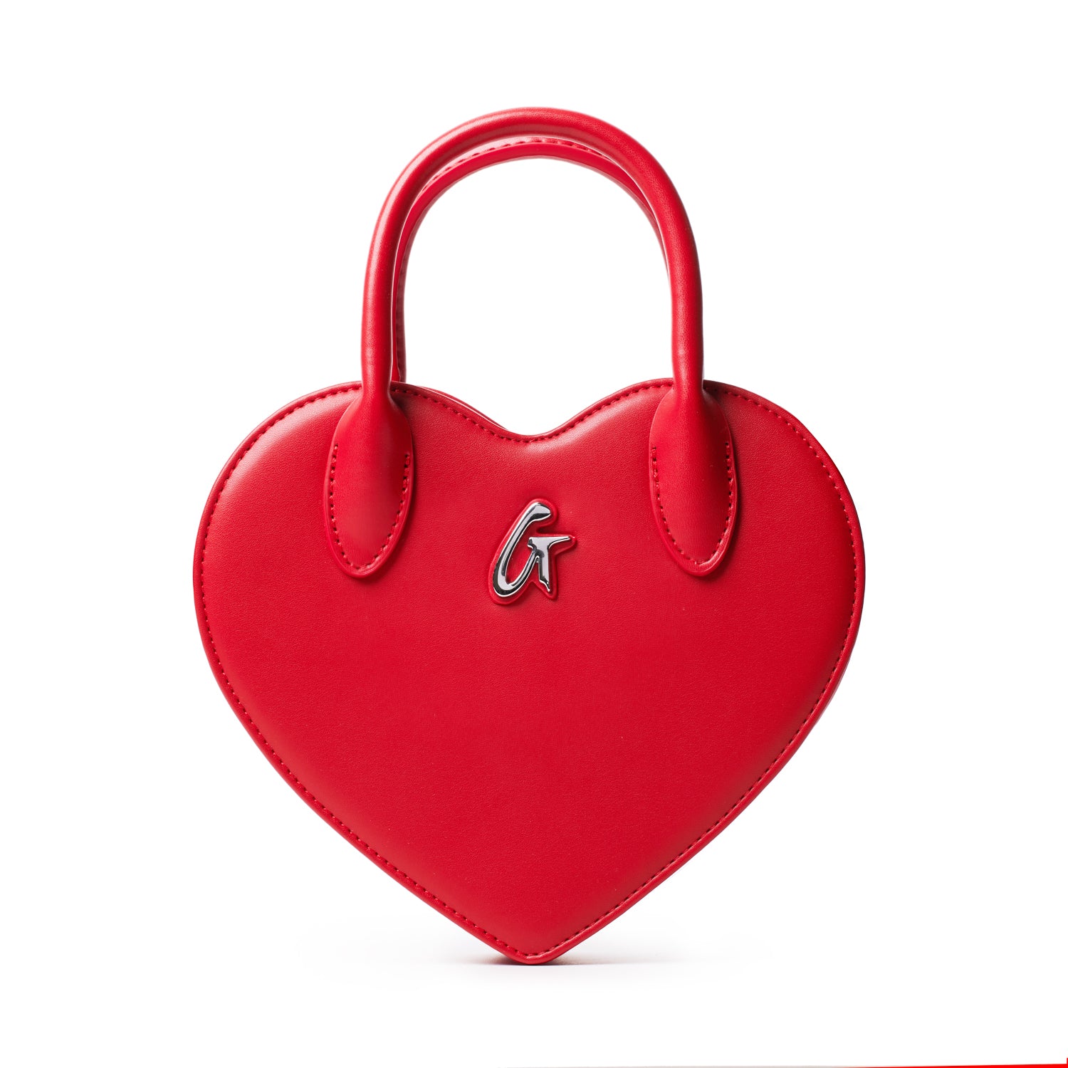 Red heart-shaped bag with a silver "G" logo, featuring a top handle and smooth leather finish.