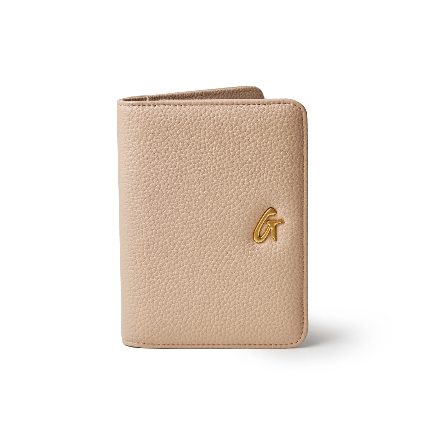 Peach-colored Pebble Passport Holder in nude with a gold logo, textured faux leather design, compact and stylish.