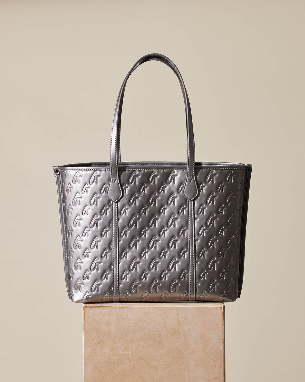 Silver Monogram Sleek Tote bag with embossed "G" pattern, dual handles, and a modern, metallic finish.