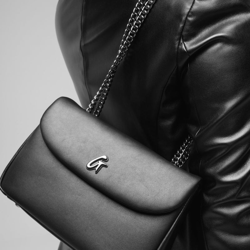 Black leather handbag with silver chain strap and "GF" logo, sleek and stylish for affordable luxury accessories.
