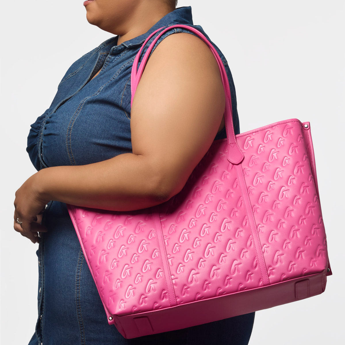 Hot pink XL monogram sleek tote bag held by a woman, showcasing its stylish design and spacious interior.