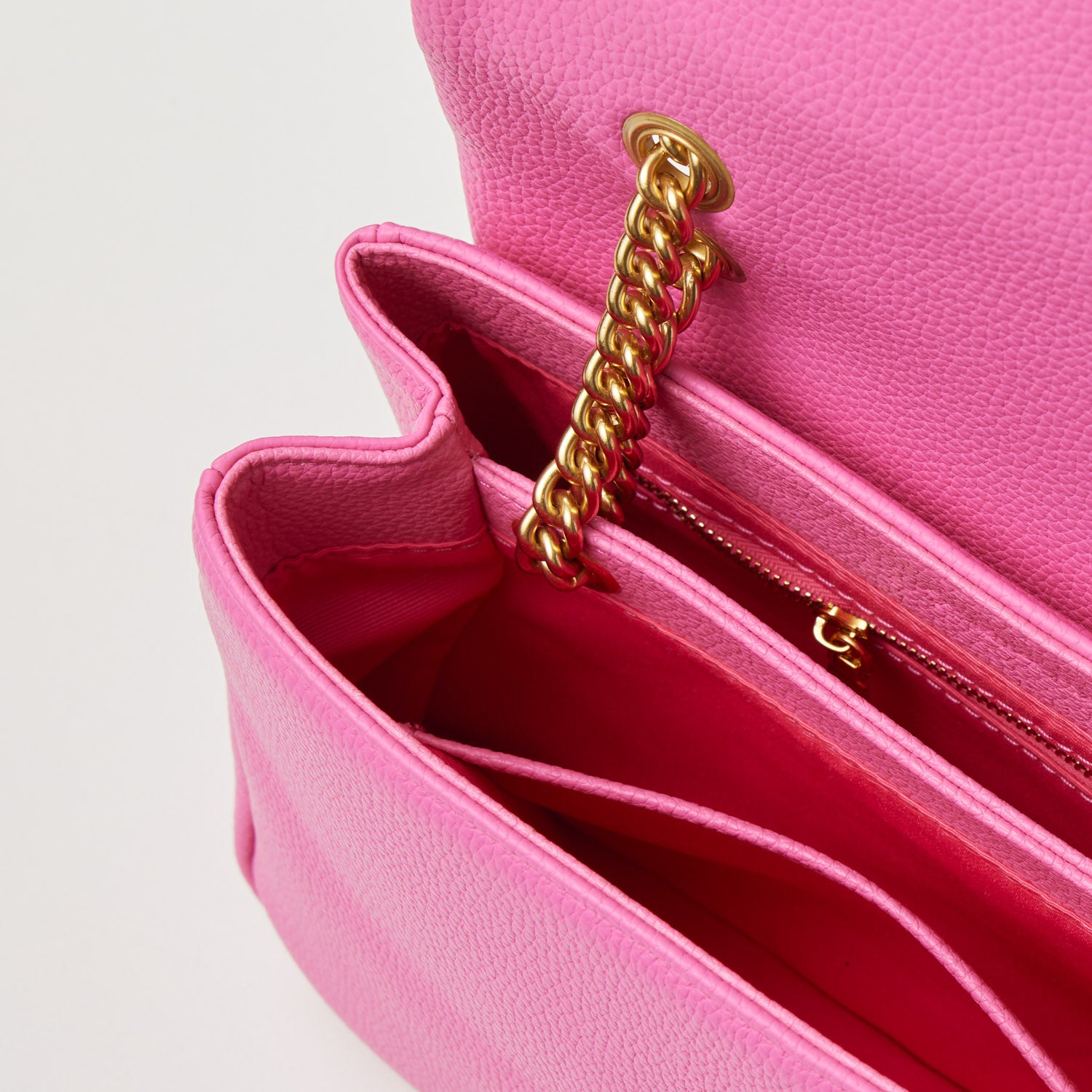 Medium hot pink pebble leather flap bag with gold chain strap and interior zip pocket, stylish and spacious for essentials.