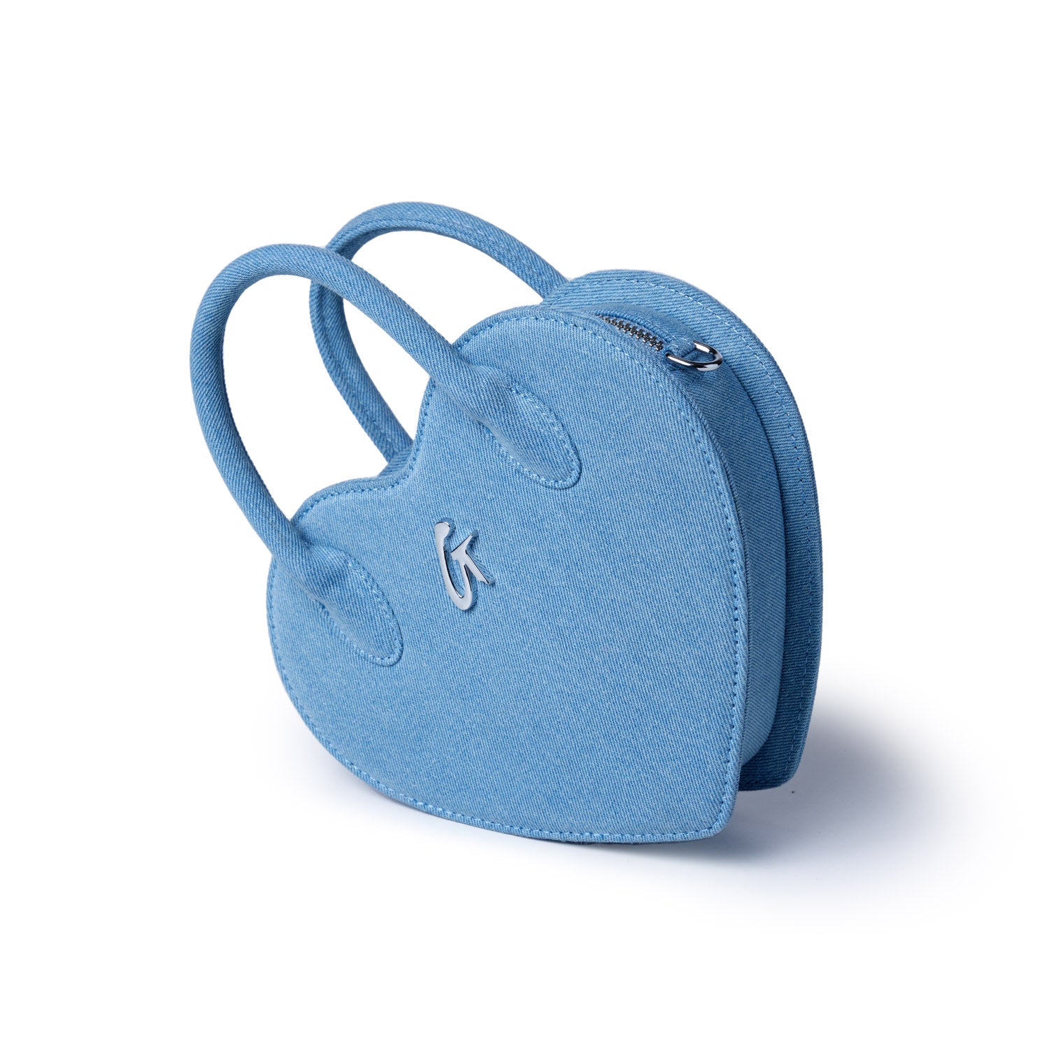 Light blue denim heart-shaped bag with handles, silver logo detail, and zipper closure, perfect for casual accessories.