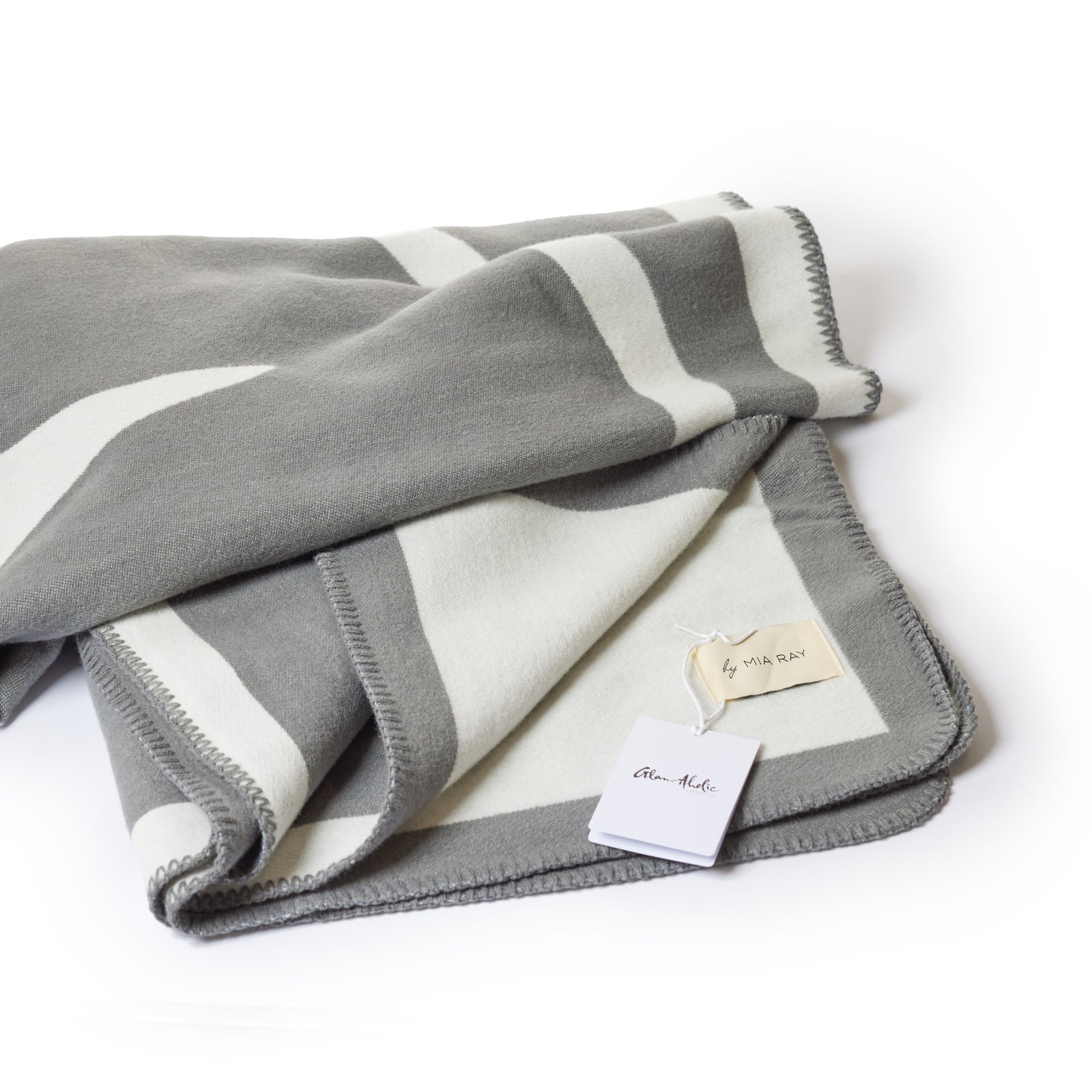 Gray classic throw blanket with white geometric patterns, folded with tags visible, on a white background.