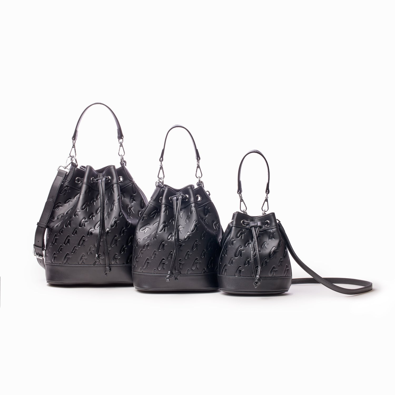 Three black mini bucket bags with monogram pattern, drawstring closure, and adjustable straps, displayed against a white background.