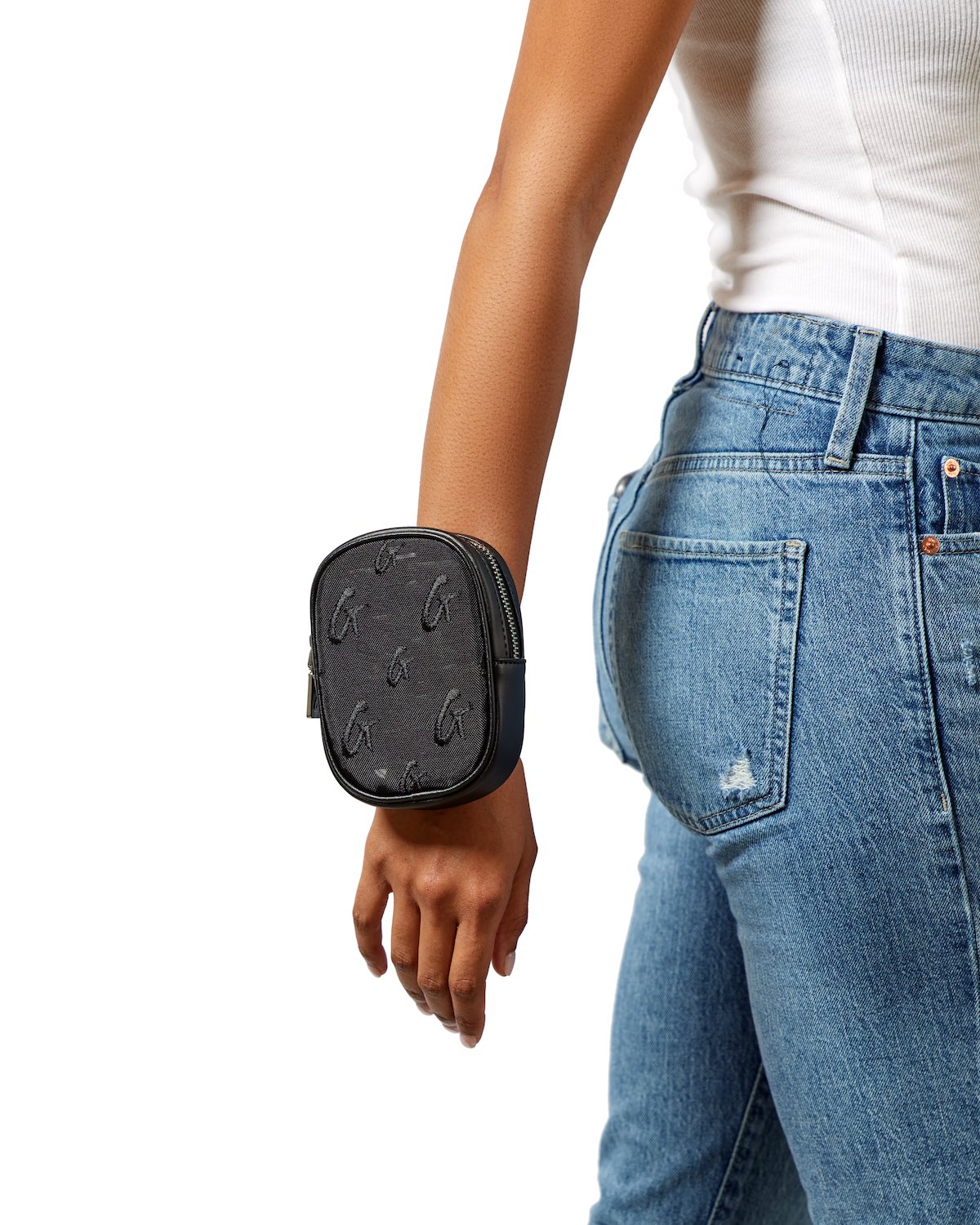 Black mesh monogram wristlet with a zip closure, worn on a person's wrist, paired with casual blue jeans and a white top.