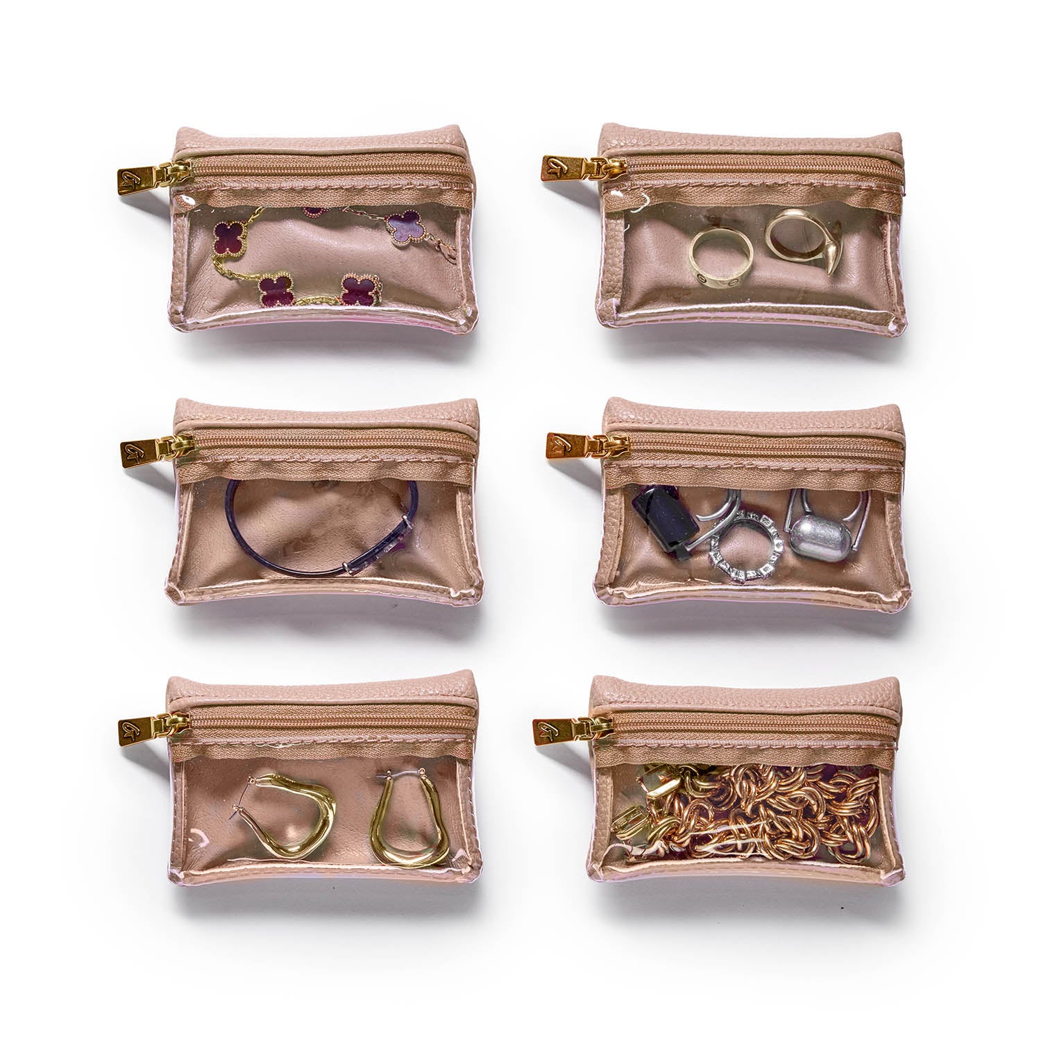 Six nude-colored pebble jewelry cases with transparent fronts, each holding different jewelry pieces and accessories.