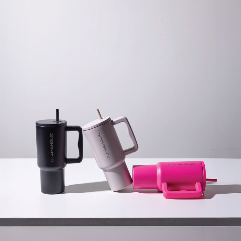 Three insulated travel tumblers in black, white, and pink on a light gray surface with a white background.