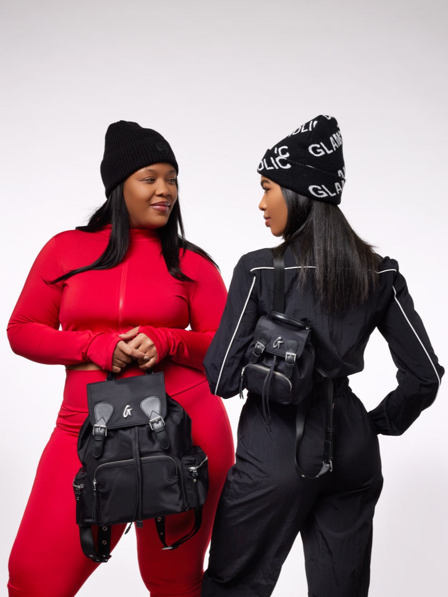 Two women model a stylish black nylon backpack, showcasing its versatility and trendy design.