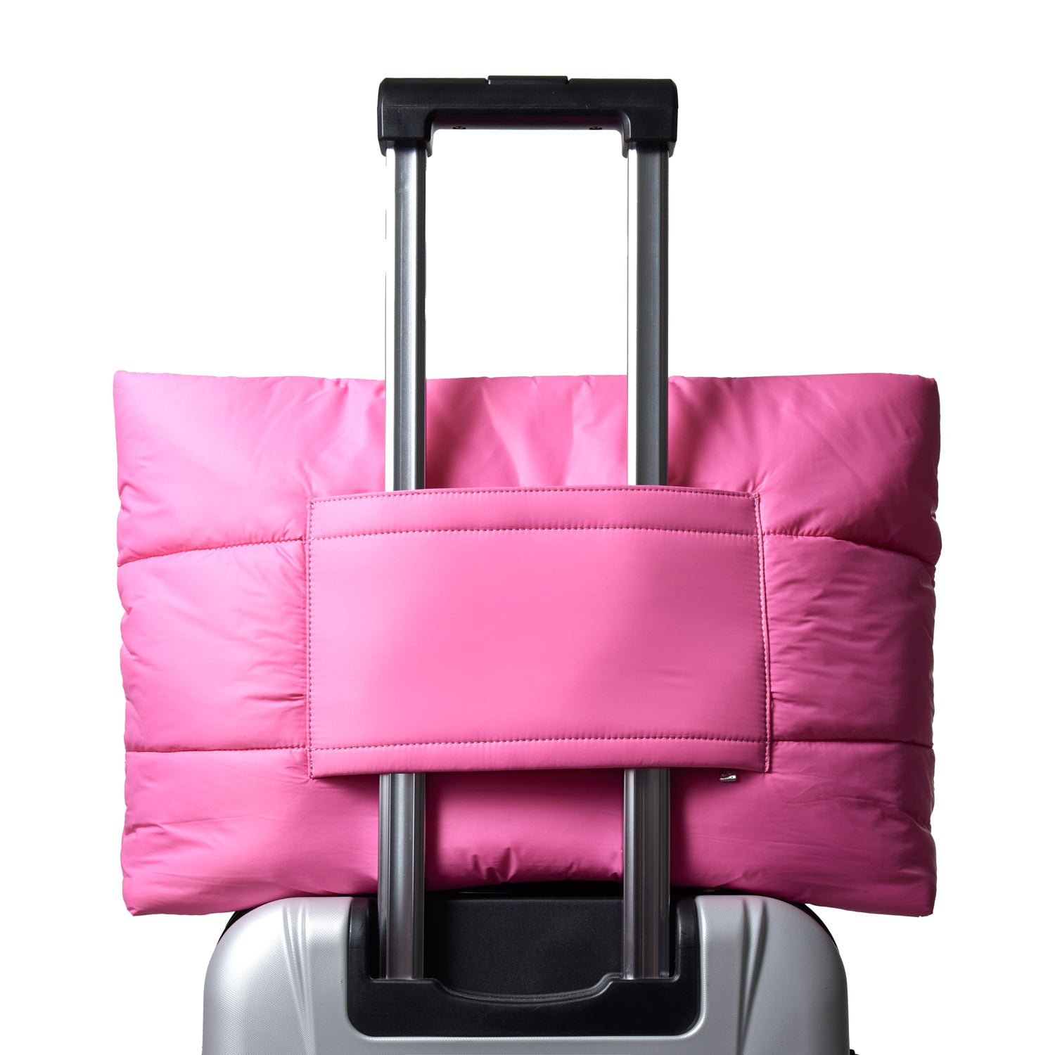 Hot pink athletic nylon tote bag secured on a suitcase handle, showcasing its stylish and functional design.