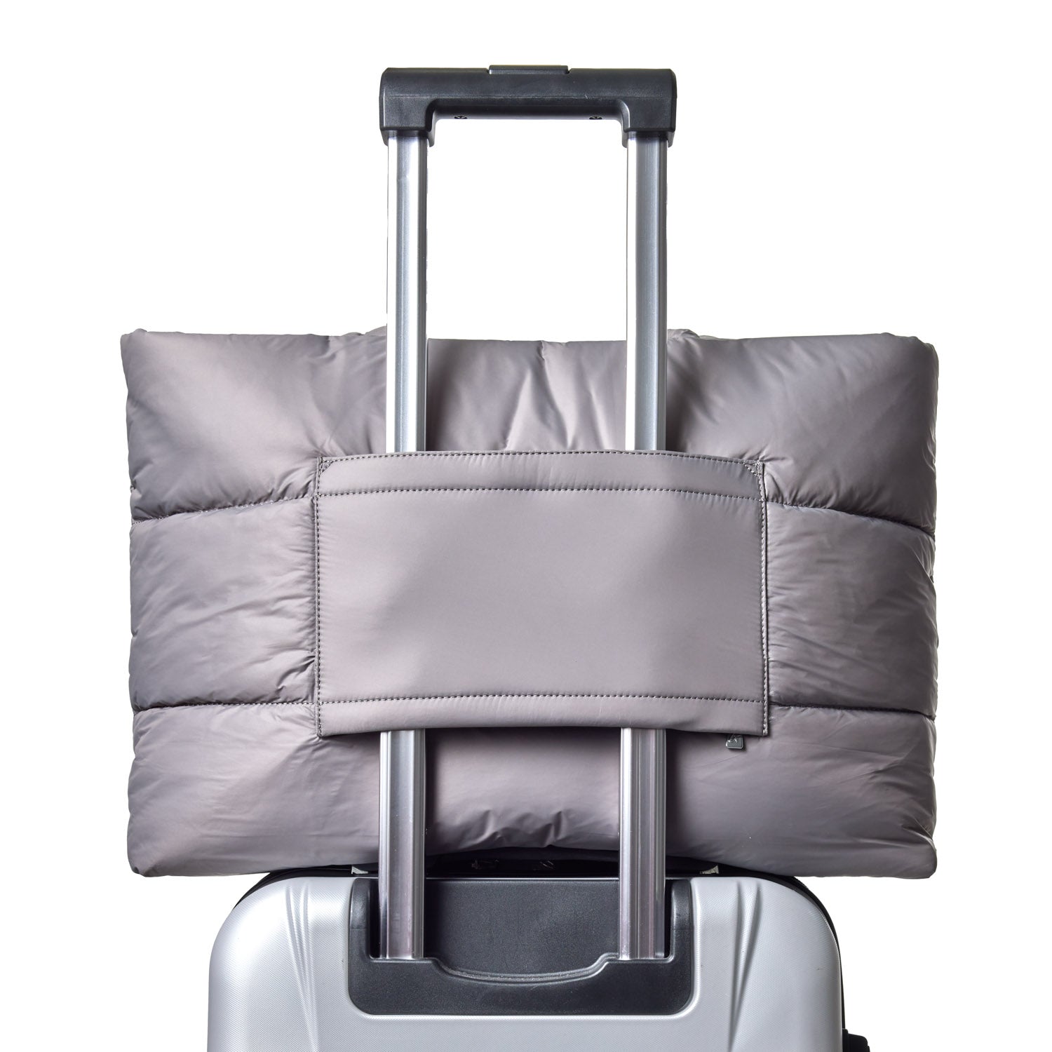 Gray athletic nylon tote secured on the handle of a wheeled suitcase, showcasing its practical design for travel.