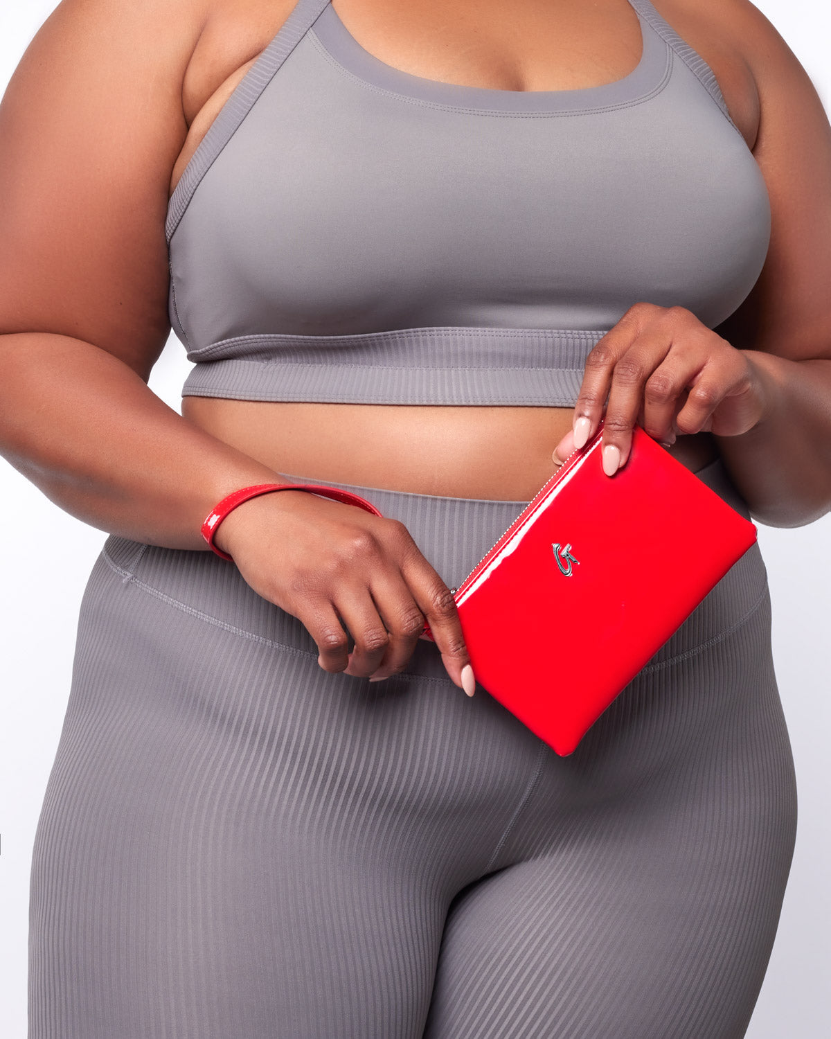 Mini standard silver wristlet in mirror red being held by a woman in athletic gray outfit.